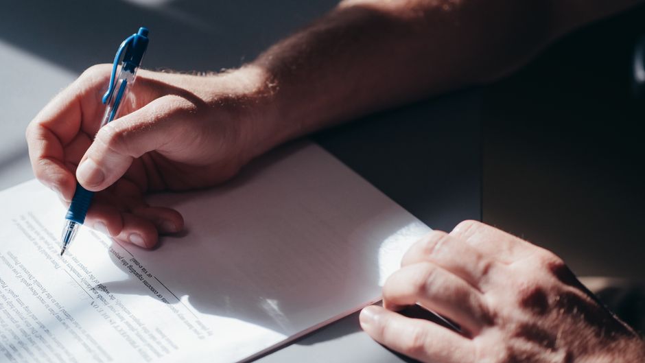 Persona firmando una carta de dimisión sobre una mesa