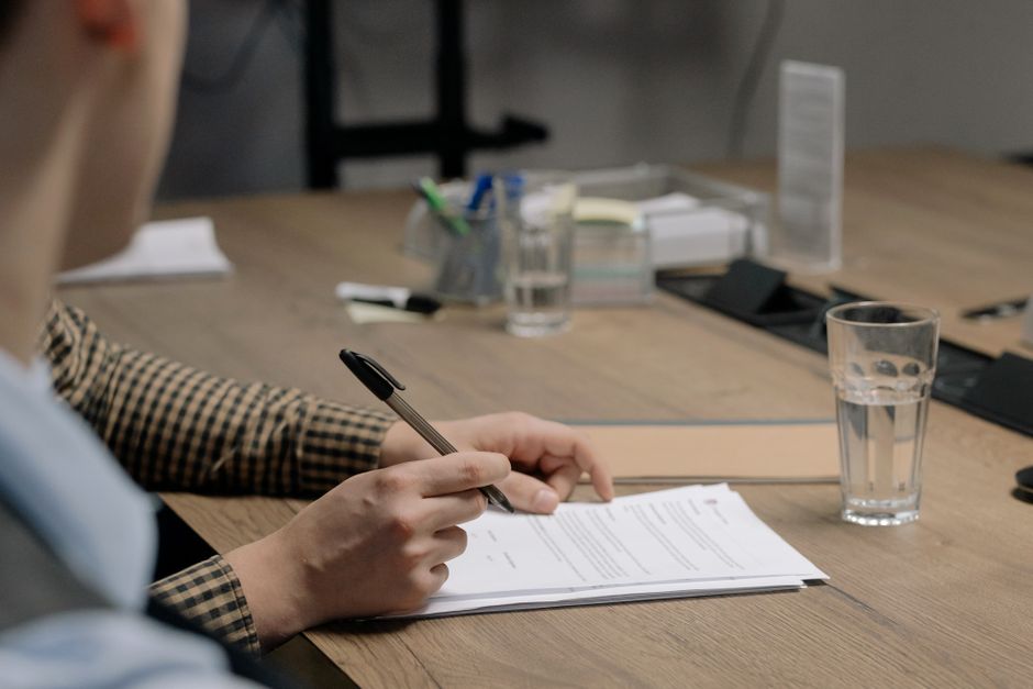 Persona firmando un documento de liquidación sobre la mesa de una oficina