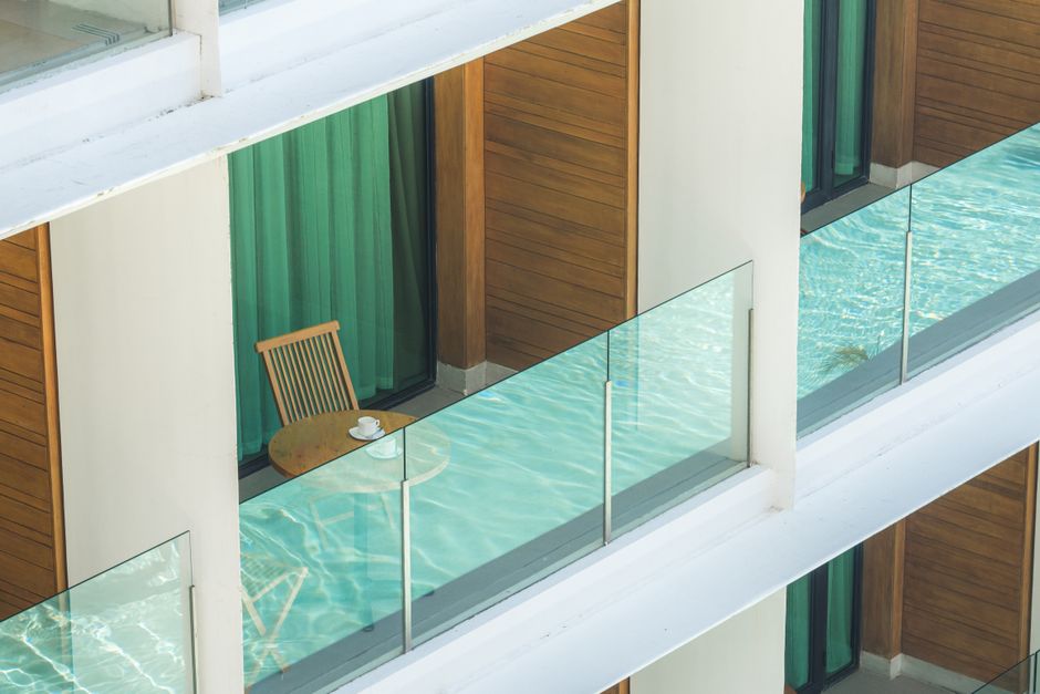 Balcón de un apartamento con una silla y una taza de café junto a una piscina