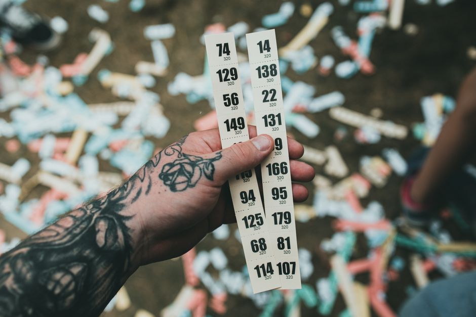 Mano sujetando dos tiras de boletos numerados sobre un suelo lleno de confeti